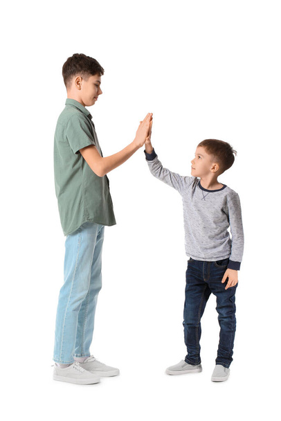 Portrait of cute brothers giving high-five to each other on white background - Foto, Imagem