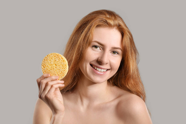 Beautiful woman with makeup sponge on grey background - Fotó, kép