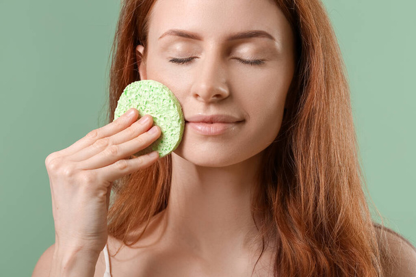 Young woman with makeup sponge on color background - Фото, изображение