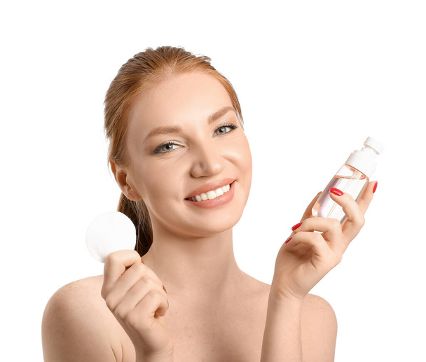 Όμορφη γυναίκα με σφουγγάρι μακιγιάζ και μπουκάλι καλλυντικών σε λευκό φόντο - Φωτογραφία, εικόνα