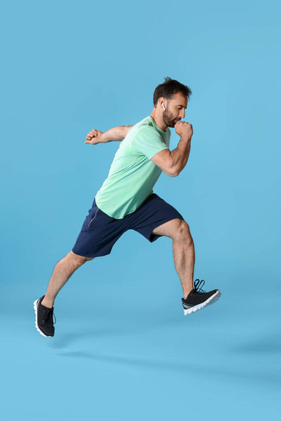 Sporty male runner on color background - Foto, Imagen