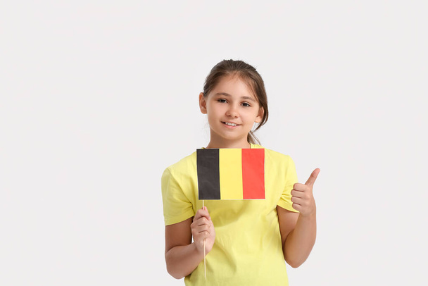 Mała dziewczynka z flagą Belgii pokazuje kciuk do góry na jasnym tle - Zdjęcie, obraz