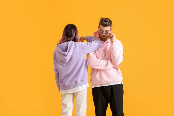 Cool young couple in hoodies on color background - 写真・画像