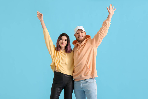 Cool pareja joven feliz en sudaderas con capucha sobre fondo de color - Foto, imagen