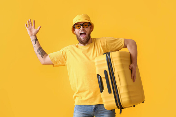 Happy young man in panama hat with suitcase on yellow background - Valokuva, kuva