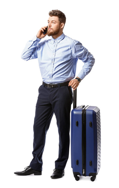 Handsome businessman with blue suitcase talking by mobile phone on white background - Photo, Image