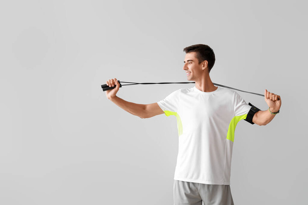 Sporty young man with jumping rope on grey background - Fotoğraf, Görsel