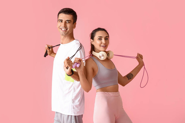 Sportliches junges Paar mit Springseilen auf farbigem Hintergrund - Foto, Bild