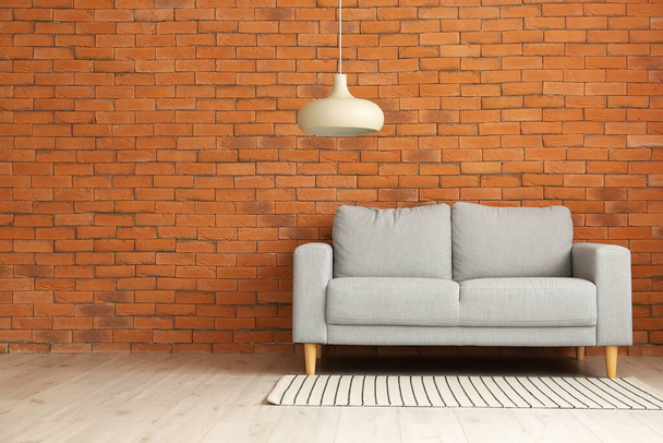Стильний диван біля цегляної стіни
 - Фото, зображення