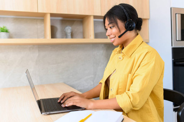 Smiling attractive multiracial young woman uses headset for talk online - Foto, Imagen