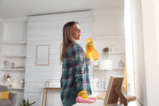 Woman with spray bottle and rag singing while cleaning at home - Photo, image