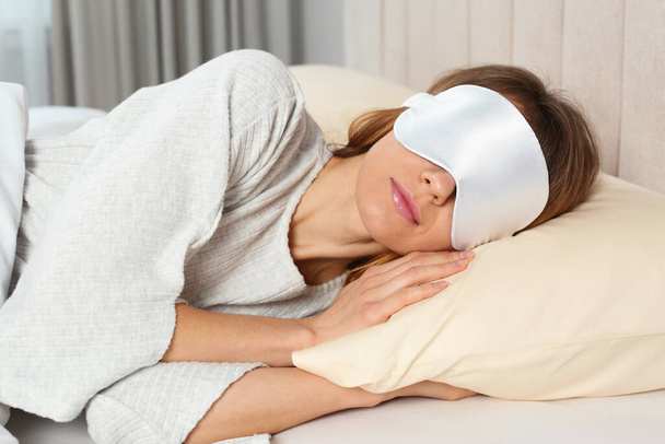 Γυναίκα με μάσκα ύπνου στο κρεβάτι στο σπίτι - Φωτογραφία, εικόνα