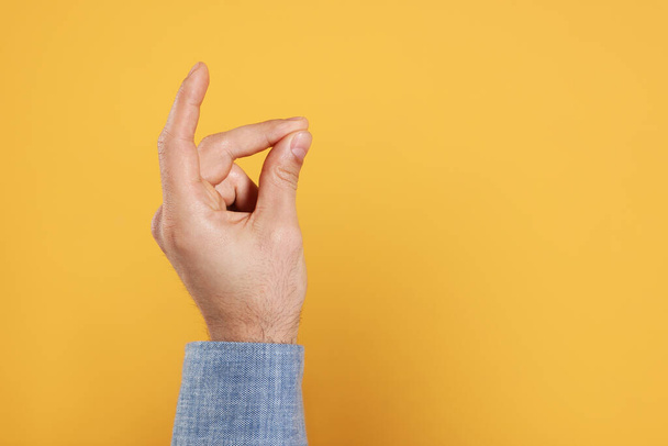 Man snapping fingers on yellow background, closeup of hand. Space for text - Fotó, kép