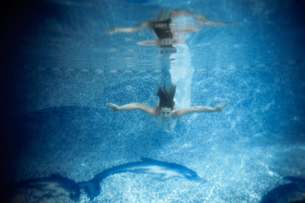 mulher sexy em vestido branco refletindo na superfície da água
 - Foto, Imagem