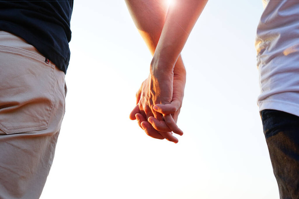 gay couple hands holding each other in the evening sunshine, concept LGBTQ pride,life,community and movement       - 写真・画像