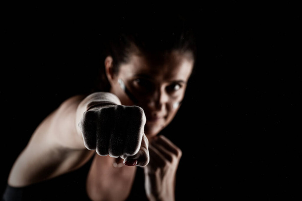 Kickboxer kirl with magnesium powder on her hands punching with dust visible. - Foto, afbeelding