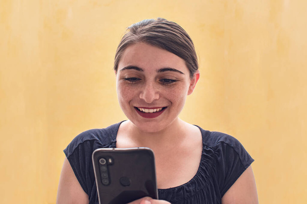 Усміхнена латинка дивиться на свої соціальні мережі на свій мобільний телефон
 - Фото, зображення