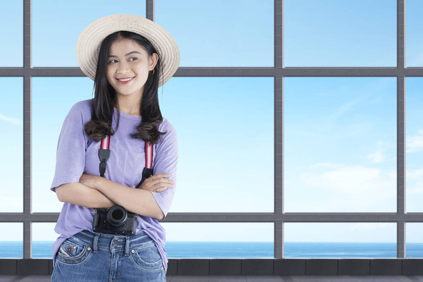 Asian woman with a hat and camera standing inside the building with blue sky background - Foto, Bild