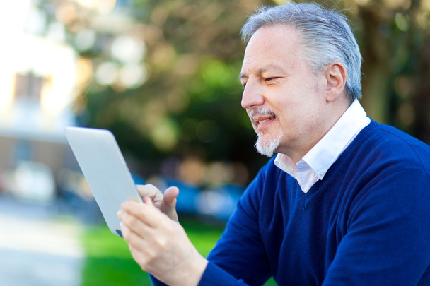 Mature man using tablet at park - Фото, изображение