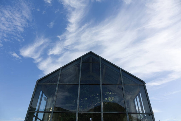 空を背景にしたガラス温室 - 写真・画像