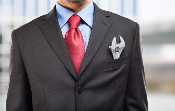 Businessman keeping a wrench in his pocket - Foto, immagini