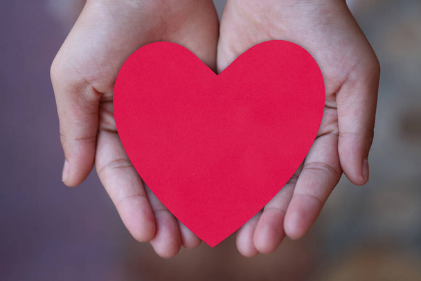 Κόκκινο χαρτί καρδιά στο χέρι στην αγάπη και την έννοια ημέρα του Αγίου Βαλεντίνου. - Φωτογραφία, εικόνα