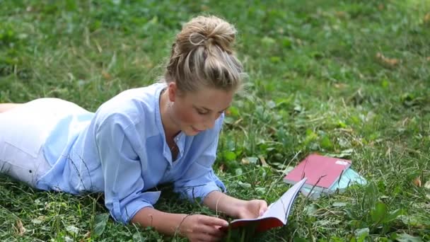 Młoda kobieta studia na trawie - Materiał filmowy, wideo