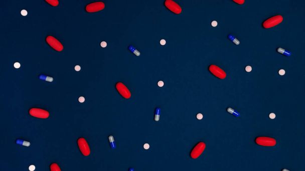 Variety of drugs in capsules and pills of different colors on a blue background - Photo, Image