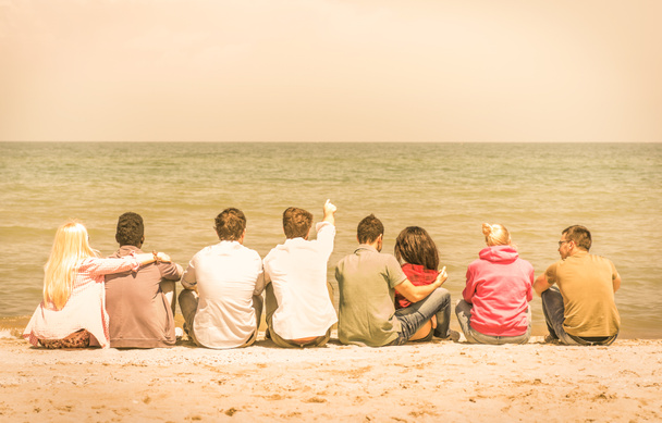 Grupo de amigos multirraciales internacionales sentados en la playa hablando entre sí y contemplando el mar - Concepto de amistad multicultural contra el racismo - Mirada cálida vintage filtrada
 - Foto, imagen