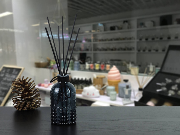 luxe aroma geur riet diffuser zwarte glazen fles zijn op zwart houten tafel met dennenappel om aromatherapie te creeren en te ontspannen ambient in mooie home geur winkel - Foto, afbeelding