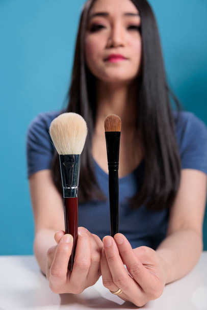 Ázsiai befolyásoló gazdaság kozmetikai kefék mutatja a kamera - Fotó, kép