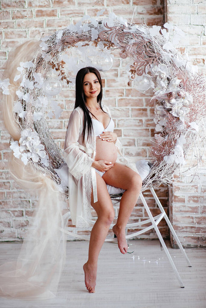 beautiful pregnant woman in white bodysuit. the beauty of the female body. cosmetics and sports for pregnant women. happiness of motherhood. a store of sexy clothes and lingerie. - 写真・画像