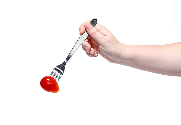 Κόκκινη ντομάτα σε ένα πιρούνι σε ένα γυναικείο χέρι που απομονώνονται σε λευκό φόντο - Φωτογραφία, εικόνα