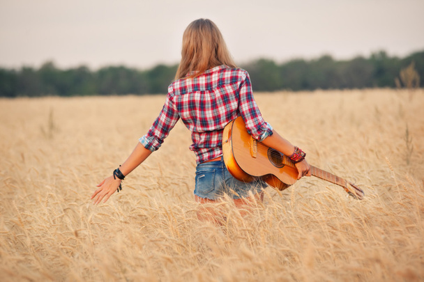 slender girl with a guitar in a wheat field. - Photo, image