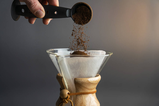pouring coffee into a glass jar on a black background - 写真・画像