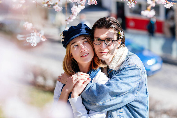 Happy young family lovely couple enjoy walking in spring blooming park, sunny garden on Petrin Hill in Prague, almond and Sakura, close-up portrait, man holds the woman's hand, relationships in love  - Photo, Image