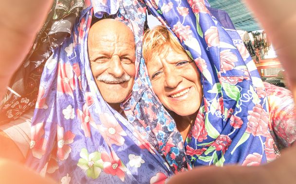 Coppia anziana felice che si fa un selfie al mercato dell'abbigliamento settimanale in giro per il mondo - Concetto di anziani attivi e interazione con nuove tecnologie e tendenze
 - Foto, immagini
