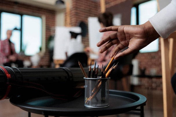 Close up of student hand taking graphic pencils in creativity studio - Foto, Imagem