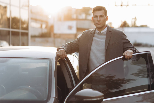 Handsome modern young man entering his car while standing outdoors - Fotó, kép