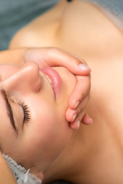 スパサロンでのきれいな女性患者のためのデトックス療法の顔マッサージ - 写真・画像