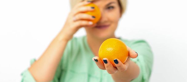 Χαμογελώντας θηλυκό διατροφολόγος κρατώντας ένα ολόκληρο πορτοκάλι, προσφέροντας και κοιτάζοντας κάμερα σε λευκό φόντο, υγιεινή διατροφή έννοια - Φωτογραφία, εικόνα