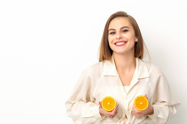 Young Caucasian smiling woman holding slices orange over isolated white background, breast health concept - Foto, Imagem