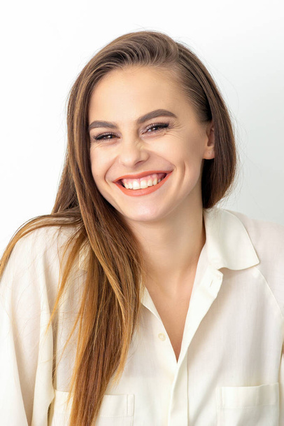 Beauty concept of woman. Portrait of a happy charming shy smiling young caucasian woman with long brown hair posing and looking at the camera over white background - Zdjęcie, obraz