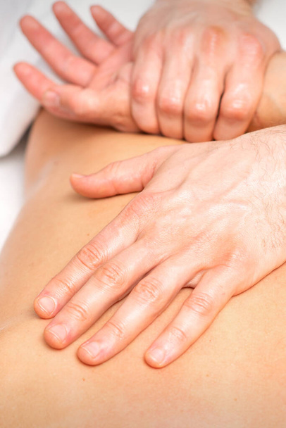 Egy férfi fizioterapeuta kinyújtja a karját egy fekve fekvő férfi hátán, közelről - Fotó, kép