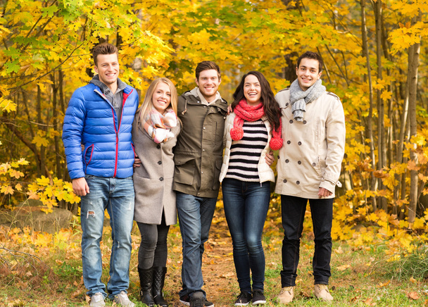 group of smiling men and women in autumn park - Foto, afbeelding
