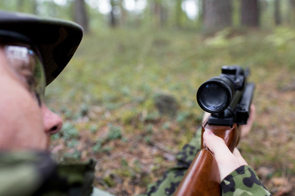 close up of soldier or hunter with gun in forest - Foto, afbeelding