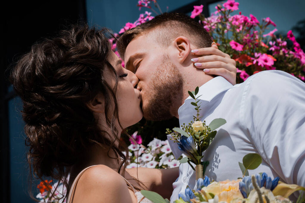 Любящая супружеская пара в красивом парке танцует и целуется. Счастливая невеста и стильный жених. Летний жаркий день - Фото, изображение