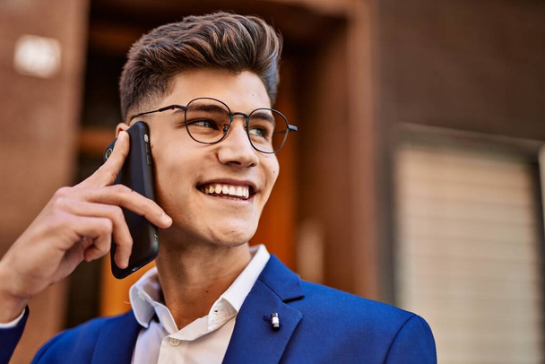 Young man talking on the smartphone wearing suit and glasses at street - Фото, изображение