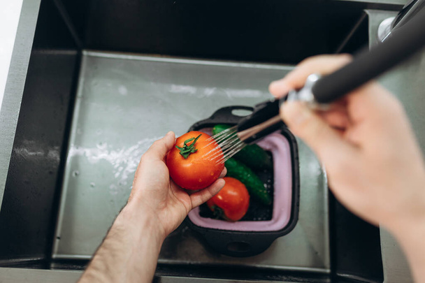 να πλένεις λαχανικά στην κουζίνα. Αγγούρια Ντομάτες - Φωτογραφία, εικόνα