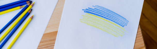 vista superior de lápices de color cerca de papel blanco con trazos azules y amarillos, pancarta - Foto, imagen